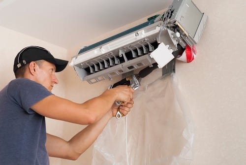 Climatisation Cap d'Ail - homme qui règle un climatiseur au plafond