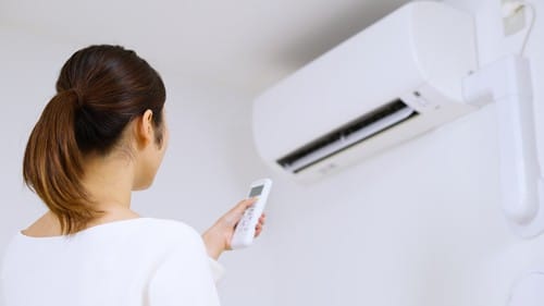 Climatisation Carpentras - femme qui tient une télécommande pour régler un climatiseur