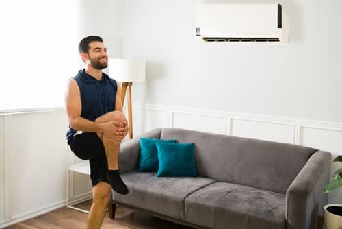 Climatisation Cavaillon - homme qui fait du sport dans son salon en dessous d'un climatiseur