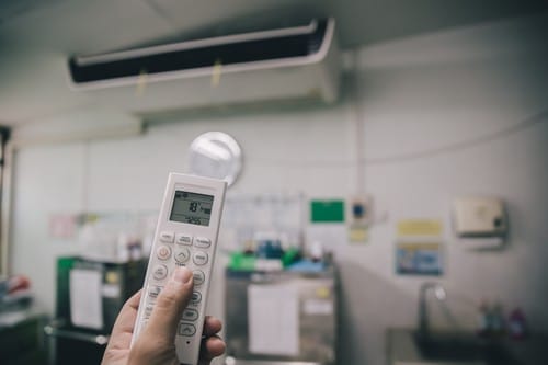 Climatisation Hautmont - main qui tient une télécommande pour régler un climatiseur