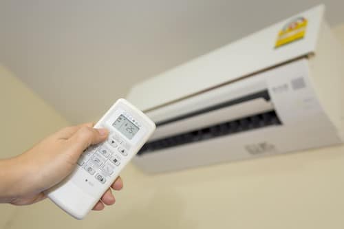 Climatisation La Madeleine - main qui tient une télécommande pour régler un climatiseur
