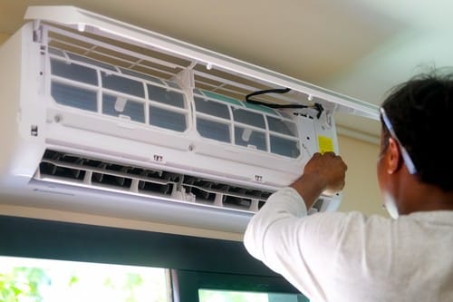 Climatisation Lapalud - homme qui règle un climatiseur au plafond