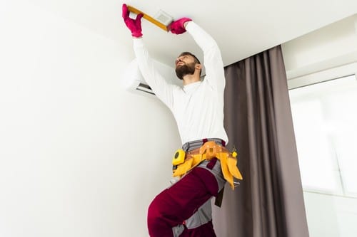 Climatisation Le Thor - homme qui règle un climatiseur au plafond