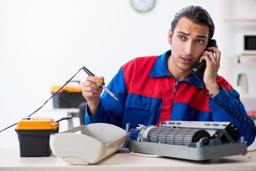 Climatisation Leguevin - homme au téléphone qui rège un climatiseur en même temps