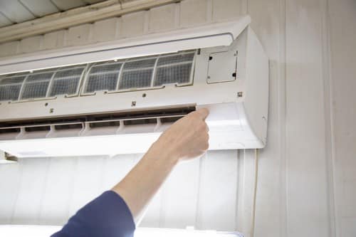 Climatisation Tourrette-Levens - main qui règle un climatiseur au plafond